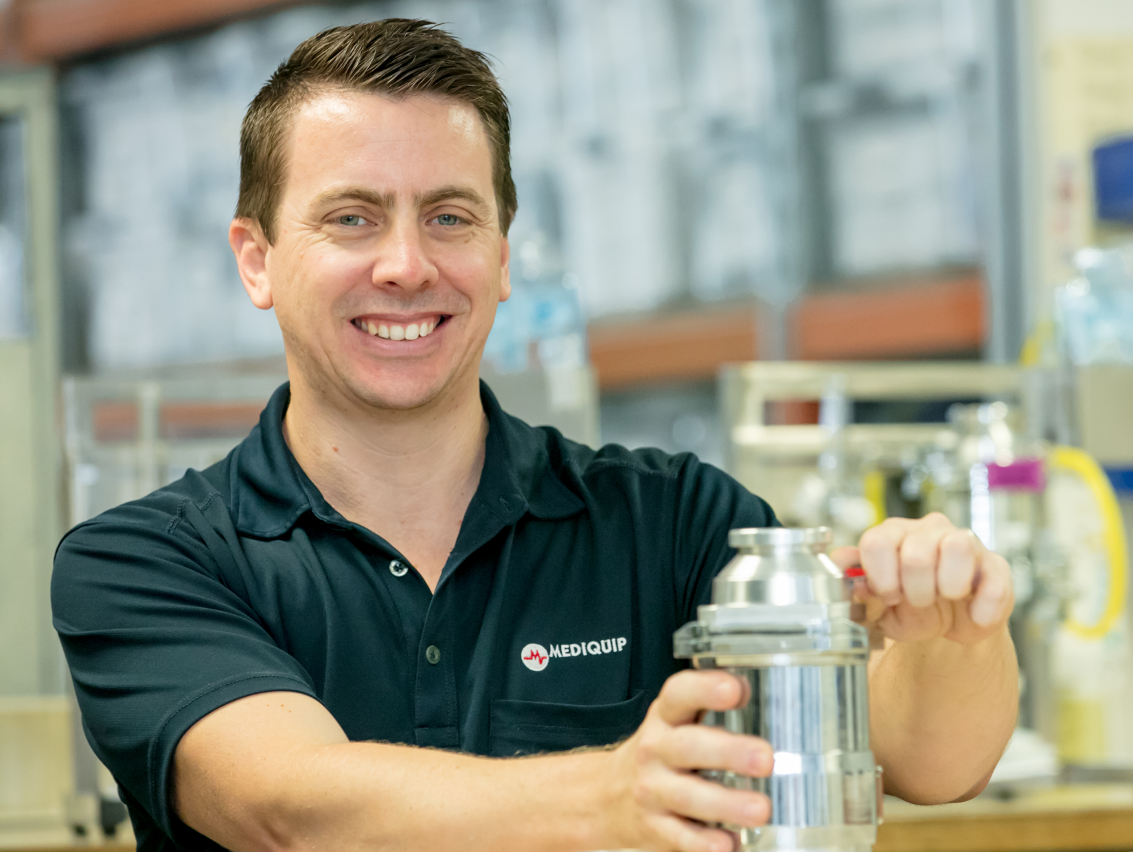 a man smiling as he adjusts some equipment with a mediquip shirt on